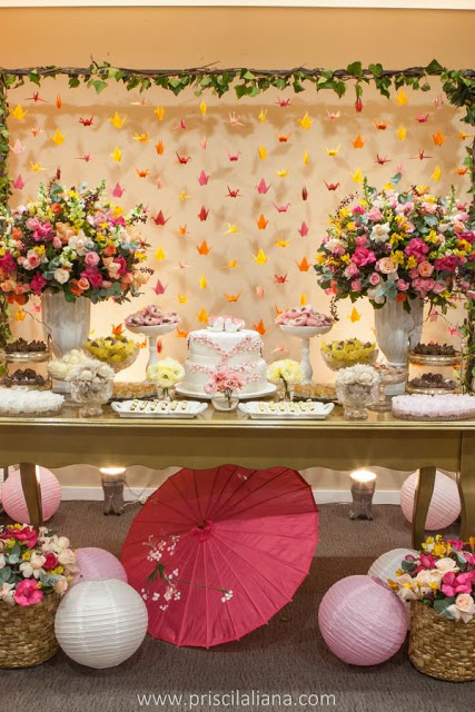 foto da mesa do bolo de um casamento com uma cortina de tsurus no fundo